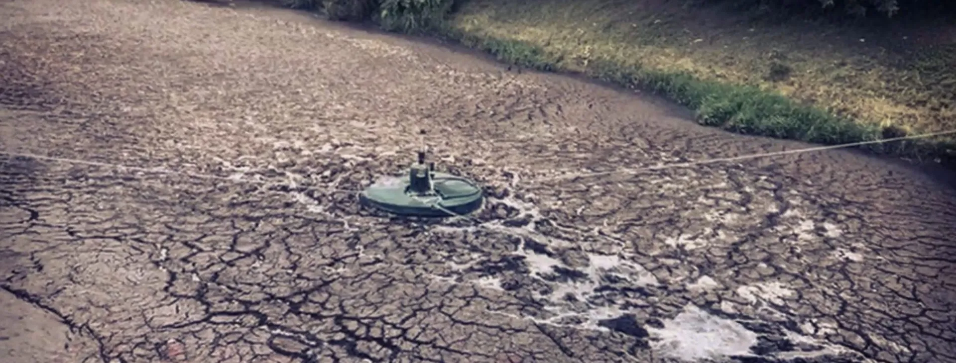 An Axbold Guardian working in a pond whose surface has crusted over with dried sludge