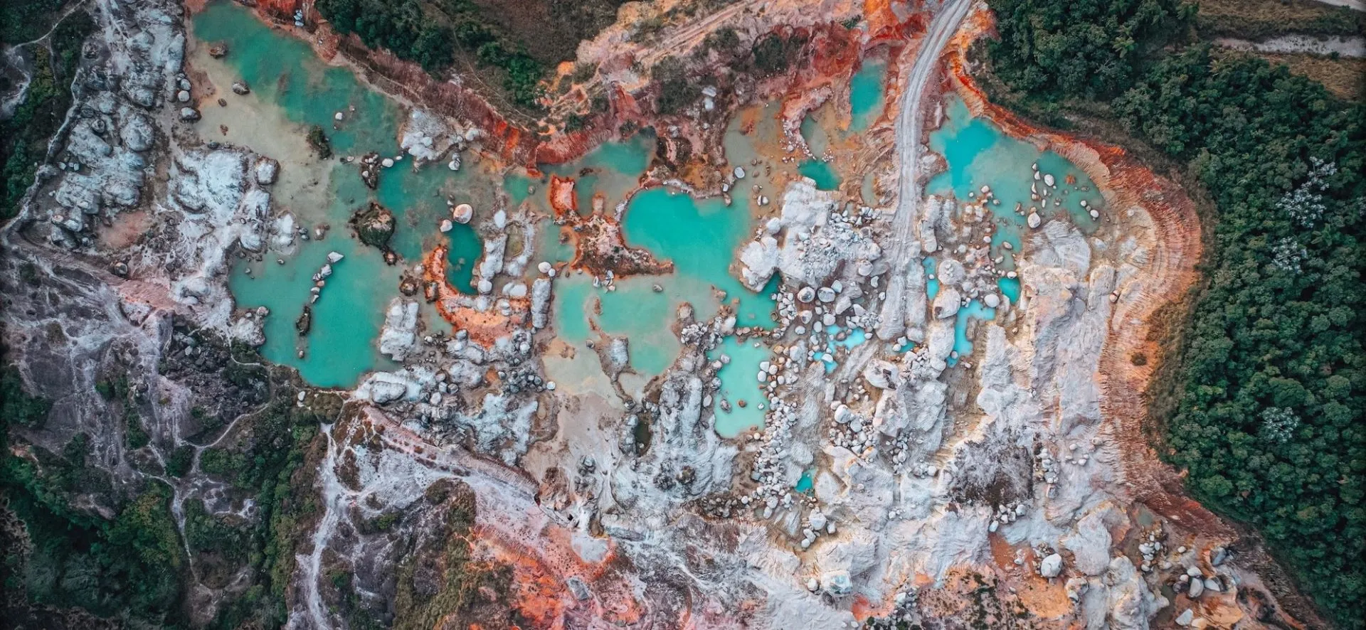 Aerial view of turquoise process water pooled among pale mine tailings