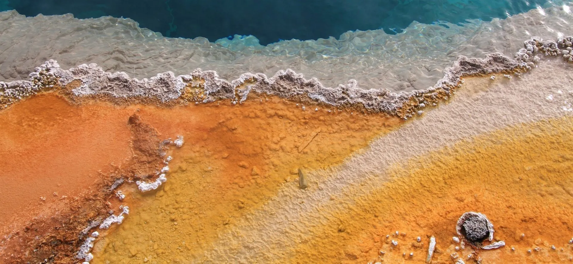 Aerial view of mineral-stained water grading from orange crust to deep blue